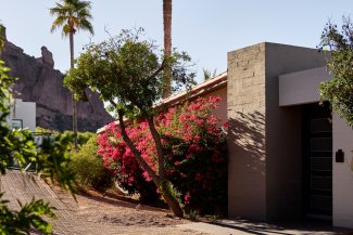 Entrance to Mountain Casita with desert landscape, red bougainvillea, and Praying Monk in background.