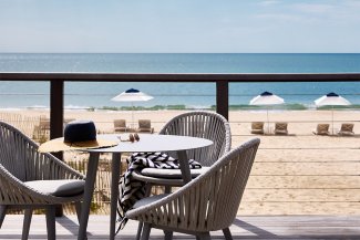 A hat and sunglasses on an outdoor dining table overlooking the ocean