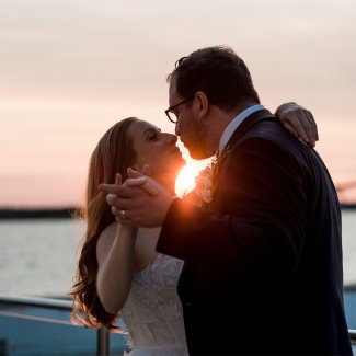 A bride and groom kiss in front of the sunset at Gurney's Montauk