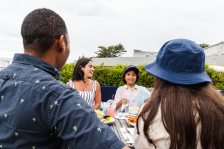 A family of four sits at a table enjoying a meal outdoors