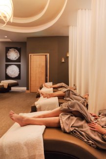Three women in robes relaxing in Sanctuary Spa's Quiet Room before treatments.