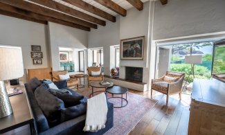 Villa Norte Living Room with southwestern design, wood floors and accents, seating area with chairs and leather couch, fireplace and flatscreen television.