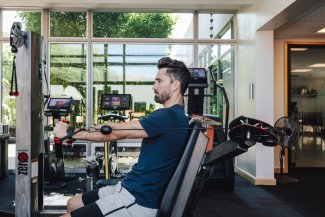 Man in fitness attire doing cable presses on cable machine in Sanctuary's fitness center.