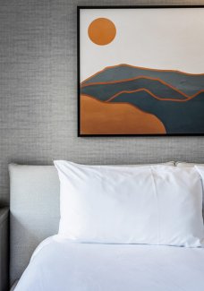 Close-up of comfortable bed and pillow with accent wall and desert mountain inspired artwork.