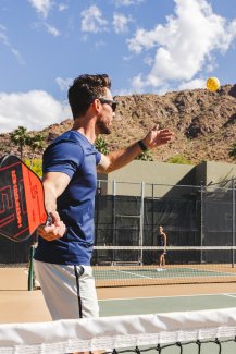 Couple playing Pickleball on Sanctuary's outdoor court with Camelback Mountain in background.