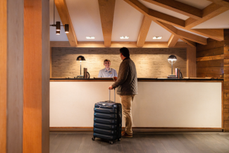 A man stands with luggage in front of the check-in desk at Gurney's Montauk Resort