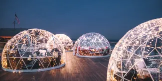 Warmly lit clear igloos against a dark blue evening sky at Gurney's Montauk Resort