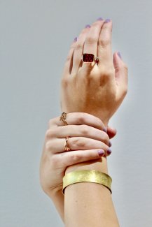 Woman's arm displaying three custom rings and a bracelet from Raintree Jewelry.