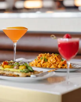Two drinks orange and pink and food