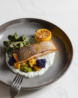 Piece of Salmon on a plate with cauliflower and lemon