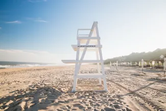 Lifeguard chair on a sunny beach, with a clear blue sky and the ocean to the left.