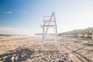 Lifeguard chair on a sunny beach, with a clear blue sky and the ocean to the left.